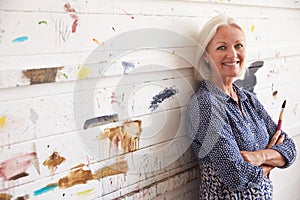 Portrait Of Female Artist Against Paint Covered Wall