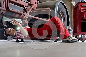 portrait female auto mechanic working underneath car