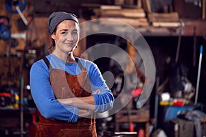 Portrait Of Female Blacksmith Wearing Headscarf Standing In Forge With Folded Arms