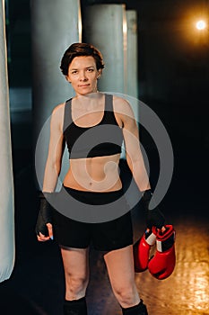 portrait of a female boxer in red gloves in the gym during training