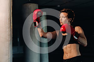 portrait of a female boxer in red gloves in the gym during training