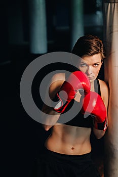 portrait of a female boxer in red gloves in the gym during training