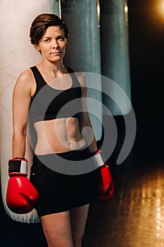 portrait of a female boxer in red gloves in the gym during training