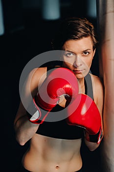 portrait of a female boxer in red gloves in the gym during training