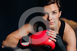 portrait of a female boxer in red gloves in the gym after training