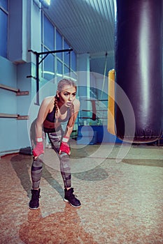 Portrait of female boxer in sport wear with fighting stance against spotlight. fitness blonde girl in sport wear