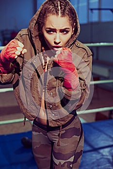 Portrait of female boxer in sport wear with fighting stance against spotlight. fitness blonde girl in sport wear