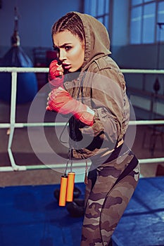 Portrait of female boxer in sport wear with fighting stance against spotlight. fitness blonde girl in sport wear