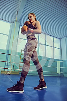 Portrait of female boxer in sport wear with fighting stance against spotlight. Sport, fitness concept. fitness blonde girl