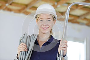 Portrait female builder carrying reel cable