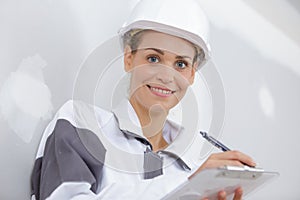 Portrait female builder writing on clipboard