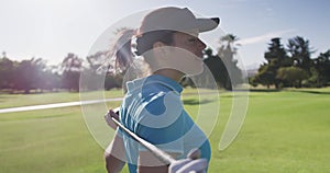 Portrait of female caucasian golf player standing with golf club around her back at golf course