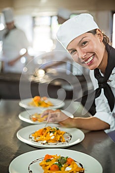 Portrait of female chef garnishing plate of food