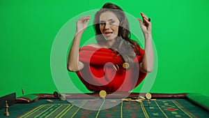 Portrait of female on chroma key green screen close shot. Elegant woman in red dress at the roulette table dropping
