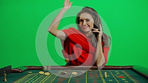 Portrait of female on chroma key green screen close shot. Elegant woman in red dress at the roulette table throws chips
