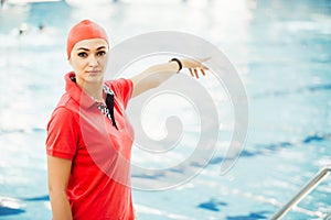 Portrait of female coach with a stop watch and clipboard by pool at leisure center