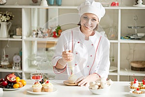 Portrait of female confectioner topping a cupcake with cream