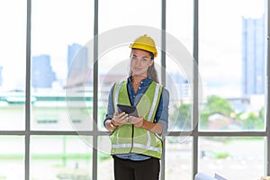 Portrait of female construction engineer workers in yellow hardhat with a tablet computer in construction site