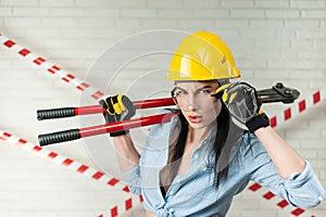 Portrait of a female construction worker in a hard hat with a bolt cutter in her hands