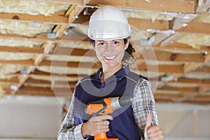 portrait female construction worker holding drill with thumbs up