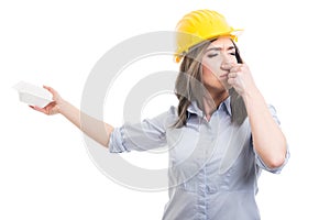 Portrait of female constructor covering nose from lunch box