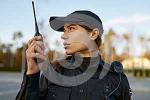 Portrait of female cop communicating on walkie-talkie