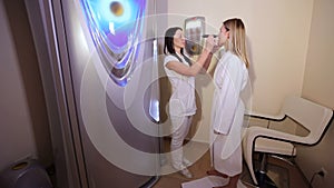 Portrait of a female cosmetologist with a client in an artificial tanning room.