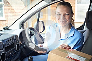 Portrait Of Female Courier In Van Delivering Package To Domestic