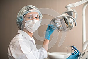 Portrait of female dentist doctor holding a lamp in the clinic