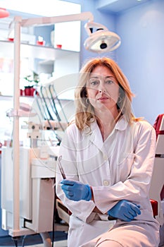 Portrait of female dentist holding medical tools in dental office.