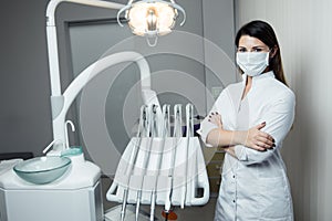 Portrait of female dentist .She standing in her dentist office. Female dentist wearing a white robe