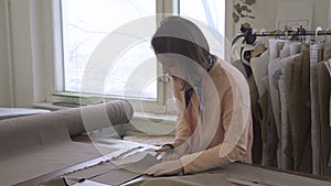 Portrait of female designer, who is cutting out the delineated details in her studio.