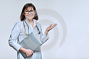 Portrait of female doctor with laptop, on light studio background