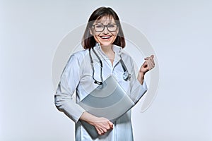 Portrait of female doctor with laptop, on light studio background
