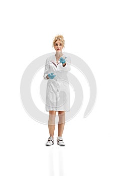 Portrait of female doctor, nurse or cosmetologist in white uniform and blue gloves over white background