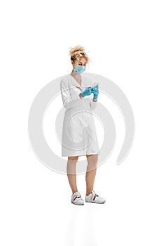 Portrait of female doctor, nurse or cosmetologist in white uniform and blue gloves over white background