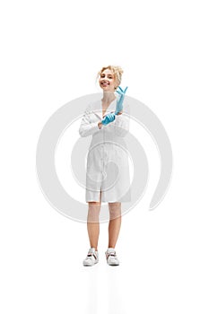 Portrait of female doctor, nurse or cosmetologist in white uniform and blue gloves over white background