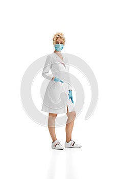 Portrait of female doctor, nurse or cosmetologist in white uniform and blue gloves over white background