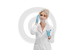 Portrait of female doctor, nurse or cosmetologist in white uniform and blue gloves over white background