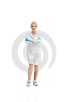 Portrait of female doctor, nurse or cosmetologist in white uniform and blue gloves over white background