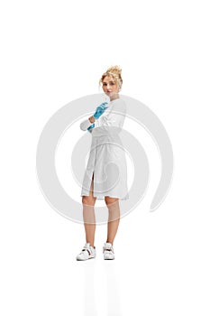 Portrait of female doctor, nurse or cosmetologist in white uniform and blue gloves over white background