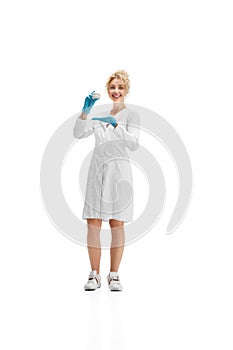 Portrait of female doctor, nurse or cosmetologist in white uniform and blue gloves over white background