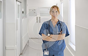 Portrait Of Female Doctor Nurse Or Surgeon Wearing Scrubs Standing In Hospital Corridor