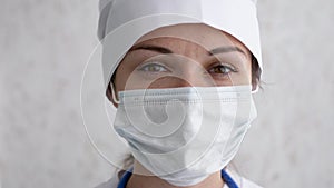 Portrait of a female doctor or nurse wearing medical cap and face mask looking at the camera. Ready to receive patients