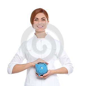 Portrait of female doctor with piggy bank