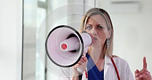 Portrait of a female doctor shouting loudly into megaphone and holding thumbs up