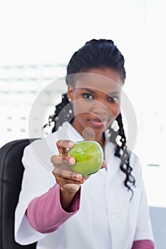 Portrait of a female doctor showing an apple