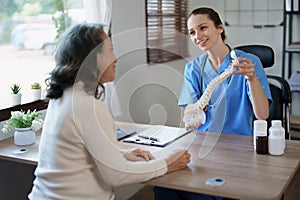 Portrait of a female doctor talking to an elderly patient about herniated disc deterioration from long hours of work.