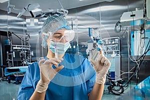 Portrait of female doctor in uniform, gloves face mask prepare syringe with antibiotic