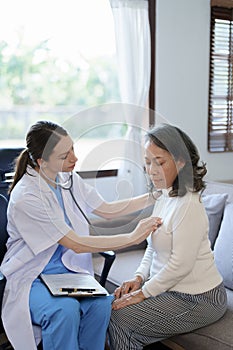 Portrait of a female doctor using a stethoscope to check the pulse of an elderly patient.